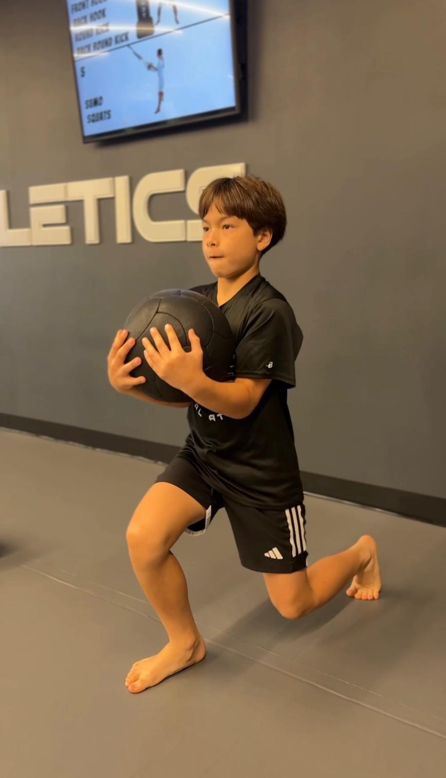 Boy doing lunges with medicine ball at IMA training