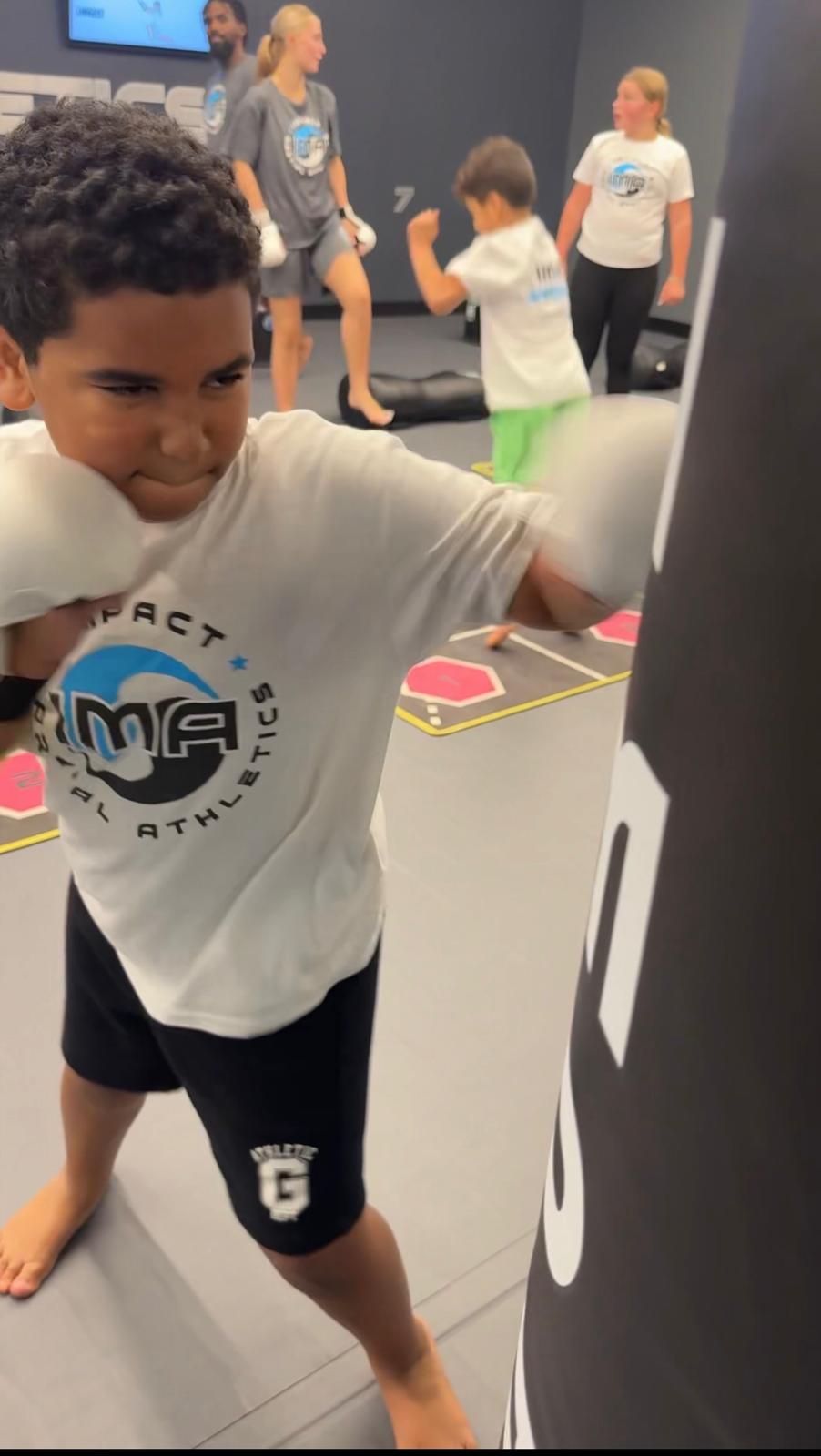 Boy throwing punches on heavy bag at IMA camp
