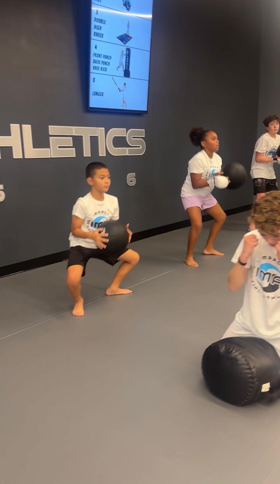Kids doing squats with medicine balls at IMA